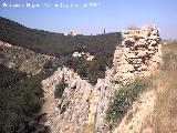 Castillo de Abrehuy. Acantilado de piedra y restos de muro sobre l, al fondo el Neveral y abajo la carretera de acceso