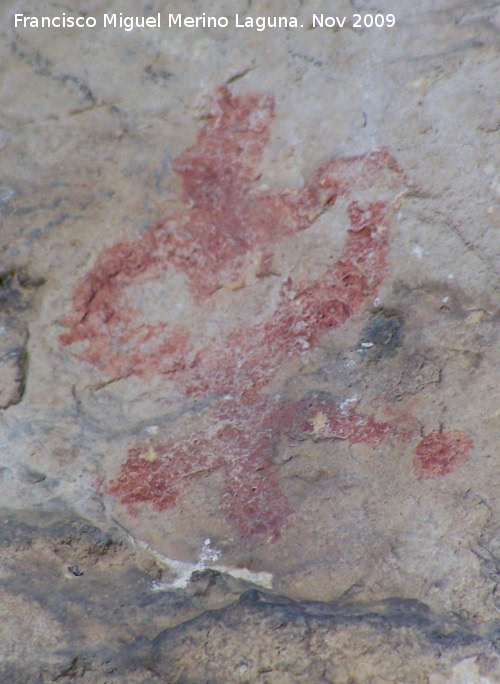 Pinturas rupestres de la Cueva de la Graja-Grupo VIII - Pinturas rupestres de la Cueva de la Graja-Grupo VIII. Antropomorfo tipo phi con dos piernas y falo, de color rojo claro. Esta en la parte inferior izquierda de la escena