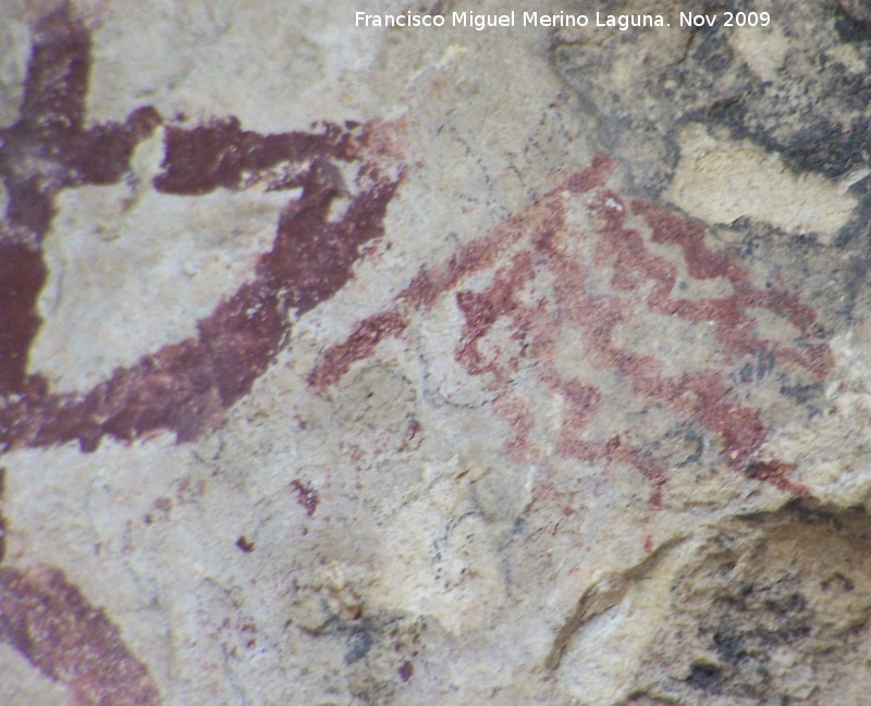 Pinturas rupestres de la Cueva de la Graja-Grupo VIII - Pinturas rupestres de la Cueva de la Graja-Grupo VIII. Barra inclinada que termina en otra barra oblicua que parten de ellas cinco barras en zig-zag